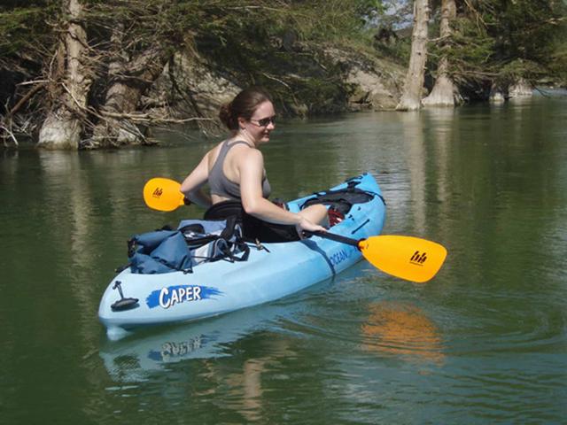 Kayaker paddling a blue kayak